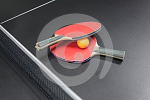 Table tennis racket with orange ball on black