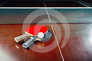 Table tennis rackets and ball, net background