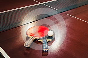 Table tennis rackets and ball, net background