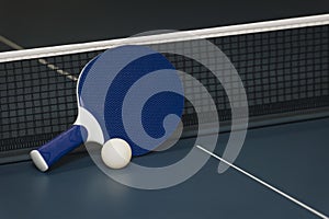 Table tennis rackets and ball and net on a blue pingpong table