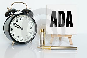 On the table there is a clock, a pen and a stand with a card on which the text is written ADA. AMERICANS WITH DISABILITIES ACT