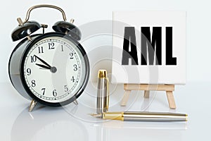 On the table there is a clock, a pen and a stand with a card on which the text is written AML. ANTI-MONEY LAUNDERING ANTI MONEY