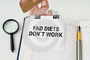 On the table there is a magnifying glass and a notepad with the inscription - Fad Diets Dont Work