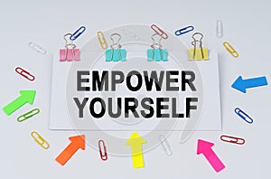 On the table there are paper clips and directional arrows, a sign that says - EMPOWER YOURSELF