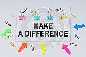 On the table there are paper clips and directional arrows, a sign that says - Make a Difference