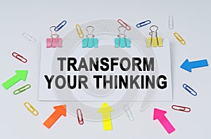 On the table there are paper clips and directional arrows, a sign that says - Transform Your Thinking