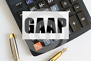 On the table there is a pen, a calculator and a business card on which the text is written GAAP. GENERALLY ACCEPTED ACCOUNTING