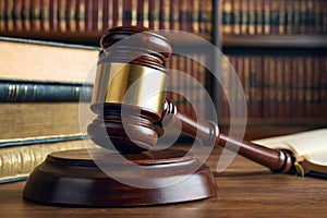 On the table there is a wooden gavel of a judge close-up on a highly blurred background