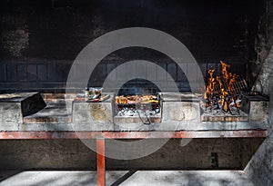 Table with three barbecues and Grill detail of food from a barbecue with sausage and chicken skewers on a sunny day in the