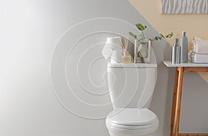 Table and toilet bowl with decor elements and necessities near color wall. Bathroom i photo