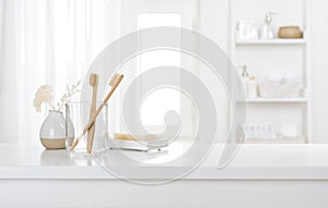 Table with toothbrushes and soap inside a bright defocused bathroom