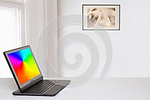 Table top on computer background. Modern portable Laptop with abstract blurred screen on white table over abstract blurred home