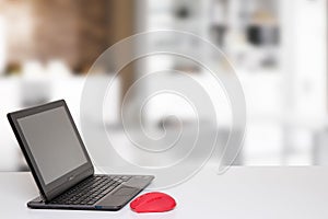 Table top on computer background. Modern portable Laptop with blank screen on white table over abstract blurred home office