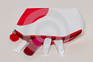 Table top on cosmetic background. Close-up of a beautiful opened red white cosmetic bag with various acial care products on a