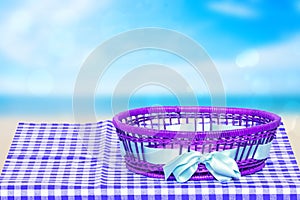 Table top on empty basket background. Empty wicker basket with blue ribbon on blue checkered tablecloth with abstract blurred