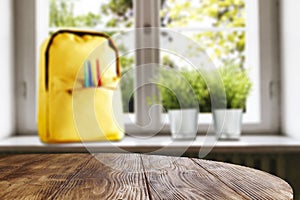 Table top with empty space for products or decoration, yellow schoolbag, red mug, blurred spring outside the window background.