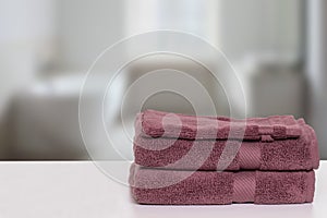 Table top on towels background. Closeup of a stack or pile of brown soft terry bath towels at a bright table against blurred