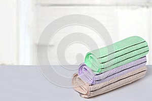 Table top on towels background. Closeup of a stack or pile of three soft terry bath towels at a bright table against blurred