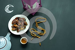 Table top view aerial image of decoration Ramadan Kareem holiday background.Flat lay date with rosary & lighting and cup of tea.