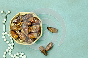 Table top view aerial image of decorations Ramadan Kareem holiday background. Flat lay date in basket with rosary and lighting.