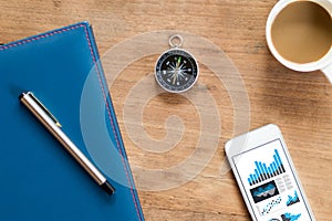 Table Top view of businessman  with compass, smart phone , pen ,notepad ,coffee cup and data report ,business and financial