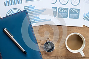 Table Top view of businessman  with compass, smart phone , pen ,notepad ,coffee cup and data report ,business and financial