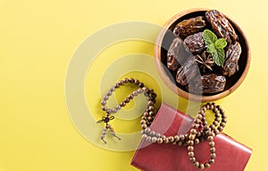 Table top view image of decoration Ramadan Kareem,  dates fruit, aladdin lamp and rosary beads on yellow  background. Flat lay