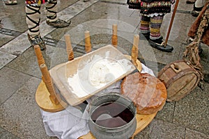 Table with traditional Bulgarian food pitka bread, kneading dough and copper menche ot buklitsa