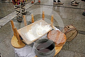 Table with traditional Bulgarian food pitka bread, kneading dough and copper menche ot buklitsa