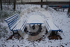 Table and two benches covered with snow in December. Berlin, Germany