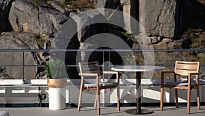 Table and two chairs on deck of river cruise boat in narrow gorge as the rocky shore moves past