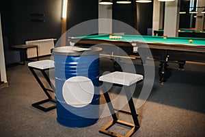 Table and two chairs near the green-covered billiard table with balls in the billiard club