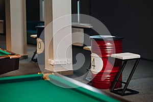 Table and two chairs near the green-covered billiard table with balls in the billiard club