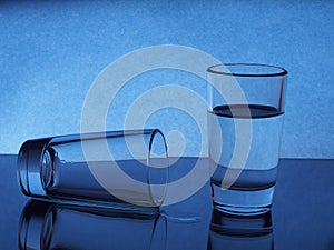 On the table two glasses. One vodka, the other is on the table, it implies the vodka