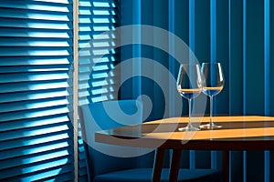 a table with two wine glasses on it in front of blue blinds