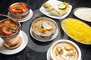 Table with typical Indian dishes, chicken curry, tandoori, tikka masala, korma, pilau rice