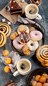 Table with various cookies, donuts, cakes and coffe cups