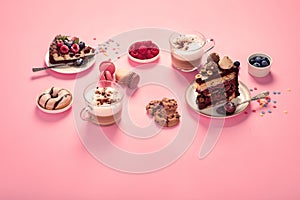 Table with various cookies, donuts, cakes, coffee cups on pink background