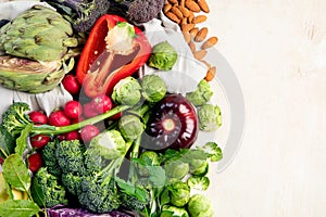Table with vegetables on a light wood background. Pepper, cabbage, broccoli, radish, garlic. Healthy eating concept