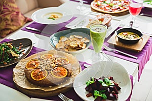 Table with vegetarian dishes - pizza, salads, pie and drinks. Food in restaurant