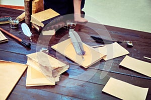 Table with vintage writing utensils. Books, paper and feather for writing in ink