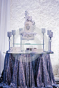 Table with a wedding cake, candles and flowers. Photo-wall, wedding decoration space or place