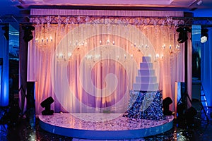 Table with a wedding cake, candles and flowers. Photo-wall, wedding decoration space or place from white and silver