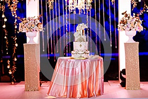 Table with a wedding cake, candles, light and flowers. wedding decoration