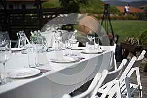 A table with white clothe glasses and chairs