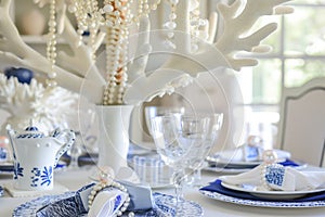 table with a white coral chandelier above, bluewhite porcelain, and pearl napkin rings photo