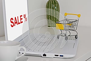 On the table is a white laptop, a small shopping cart. The concept of online shopping during sales and discounts