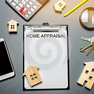 Table with wooden houses, calculator, coins, magnifying glass with the word Home appraisal. The contract for real estate appraisal photo