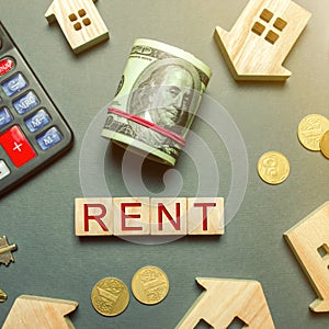Table with wooden houses, calculator, coins, magnifying glass with the word Rent. The concept of rental housing. Rent an apartment