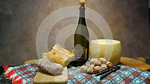 Tablecloth with bottle of wine, salami, bread, cheese, nuts and old nutcracker